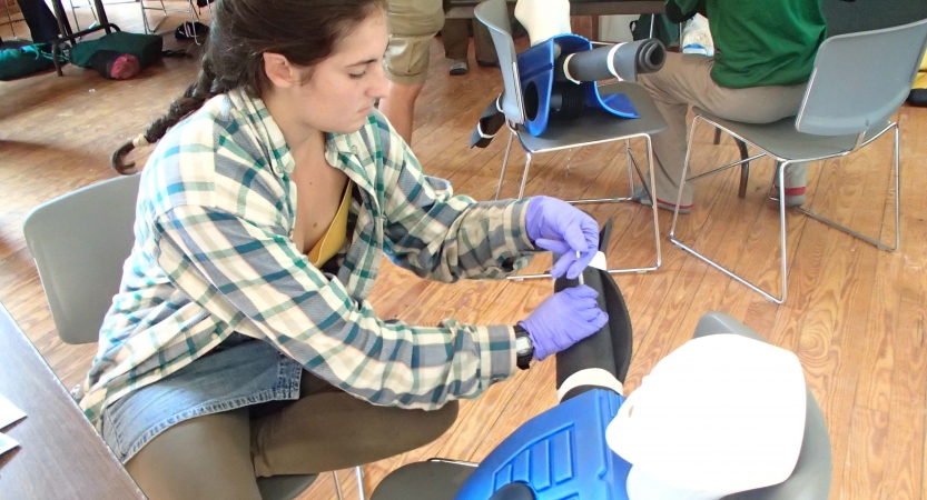 A person participating in a wilderness first aid course practices skills on an ankle. 